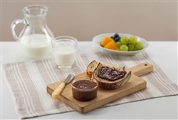 chocolate spread on toast and cutting board with milk and fruit in background